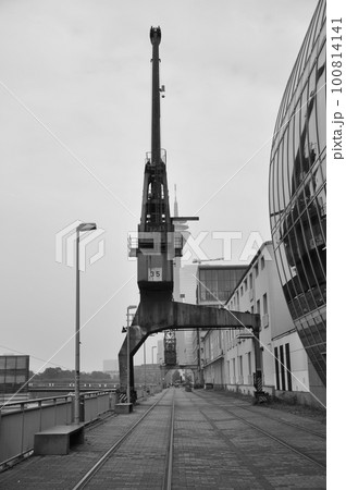 Vertical grayscale shot of an old cargo crane in the Media Harbor in Dusseldorf, Germany. 100814141