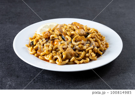 Traditional Spanish fideua. Noodle paella on black background Traditional Spanish fideua. Noodle paella on black background 100814985