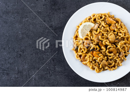 Traditional Spanish fideua. Noodle paella on black background. Top view. Copy space Traditional Spanish fideua. Noodle paella on black background. Top view. Copy space 100814987