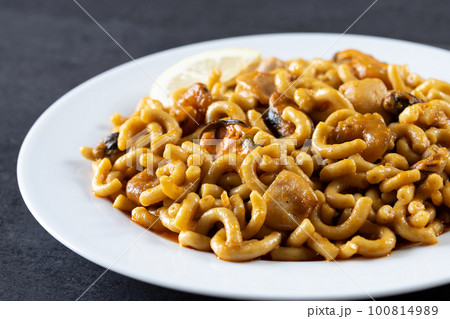 Traditional Spanish fideua. Noodle paella on black background Traditional Spanish fideua. Noodle paella on black background 100814989