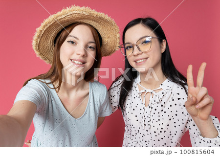 Two beautiful young women, sisters - twins on pink background Two beautiful young women, sisters - twins on pink background 100815604
