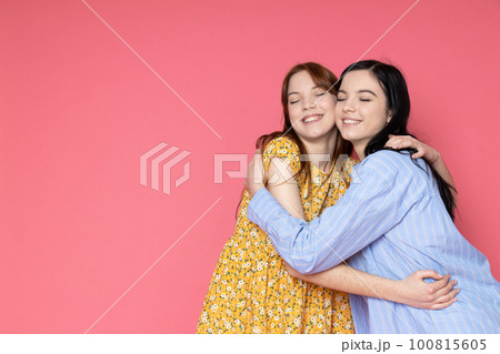 Two beautiful young women, sisters - twins on pink background Two beautiful young women, sisters - twins on pink background 100815605