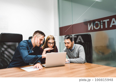 Colleagues having a meeting, brainstorming ideas for a project in a bright white office 100815948