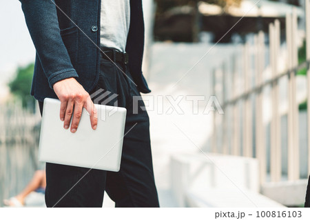 Waist down unrecognizable man side view holding a digital tablet in his hand outside 100816103
