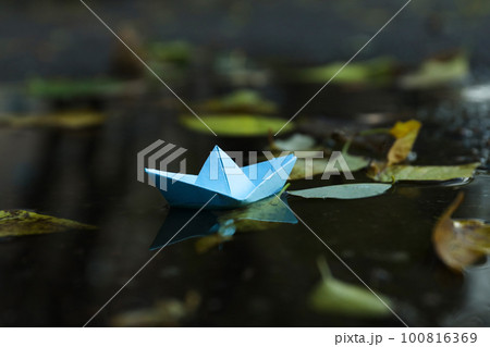 Paper boat in puddle outdoor in rainy weather 100816369