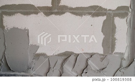 Gray wall of foam blocks on glutinous solution. Application of the solution to the wall from foam blocks. Gray wall of foam blocks on glutinous solution. Application of the solution to the wall from foam blocks. 100819308