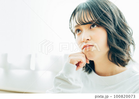 部屋で考え事をする若い女性 100820073