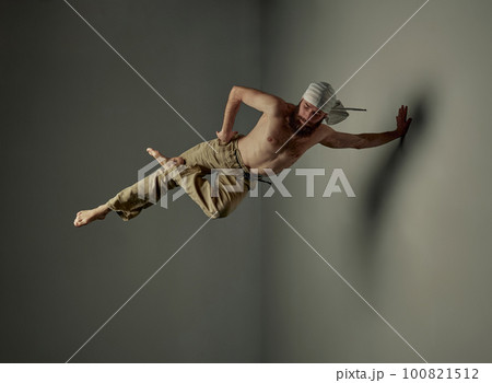 Image of bearded young man with strong muscular shirtless body training, doing yoga exercises, standing on one hand over studio background 100821512