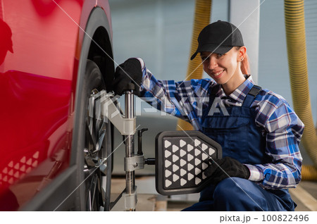 A female auto mechanic makes a camber. Woman working in a car service. A female auto mechanic makes a camber. Woman working in a car service. 100822496