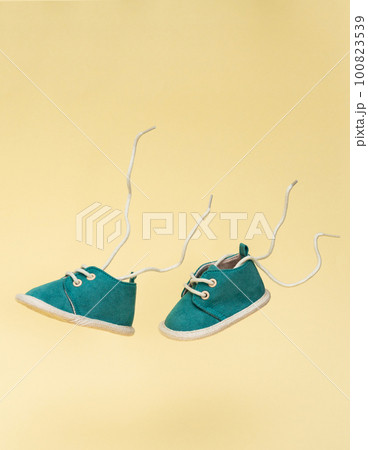 Flying baby shoes with flying laces. Newborn baby concept with levitation effect Flying baby shoes with flying laces. Newborn baby concept with levitation effect 100823539