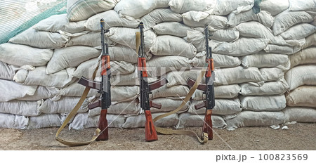 Three Kalashnikovs standing near sandbagged fortifications. AK-74 outdoor Three Kalashnikovs standing near sandbagged fortifications. AK-74 outdoor 100823569