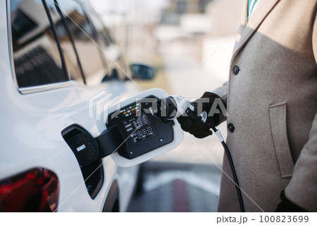 Close up of senior man charging electric car. 100823699