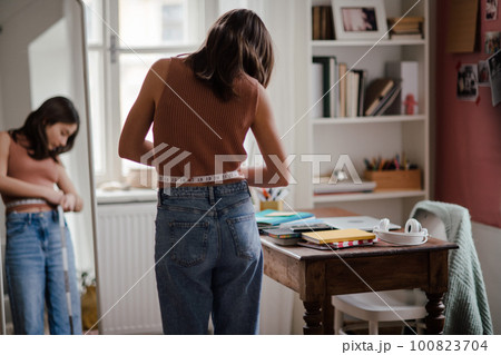 Young teenage girl looking in the mirror in her room. Young teenage girl looking in the mirror in her room. 100823704