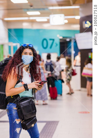 Public transport station destination. latin mid woman vacation with smartphone. with face mask Public transport station destination. latin mid woman vacation with smartphone. with face mask 100827518