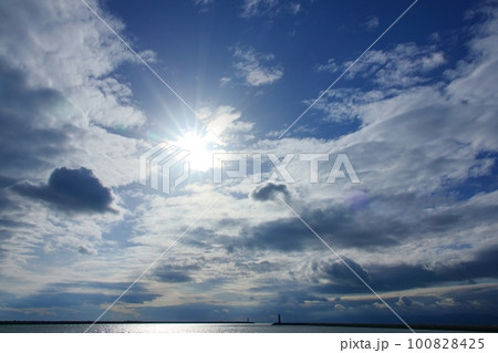 多様な雲が広がった午後の空と太陽が海に反射した港の風景・春・空主体・230318pm 100828425