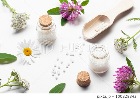 Composition of homeopathic medicines and medicinal plants on a white table Composition of homeopathic medicines and medicinal plants on a white table 100828843