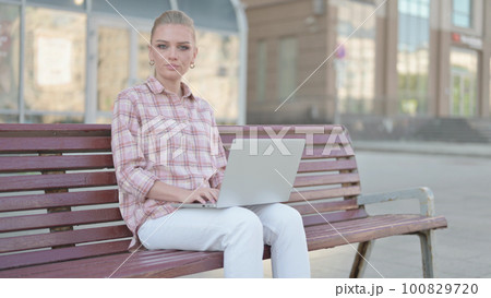 Rejecting Young Woman in Denial While using Laptop Sitting Outdoor on Bench 100829720