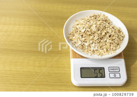 デジタルキッチンスケールでオートミール（オーツ麦）を量るイメージ 100829739