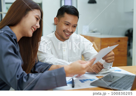 startup business, portrait of two entrepreneurs using computers and financial budget documents to make marketing plans to increase profits. 100830205
