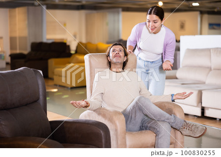 couple chooses comfortable armchair in furniture store couple chooses comfortable armchair in furniture store 100830255