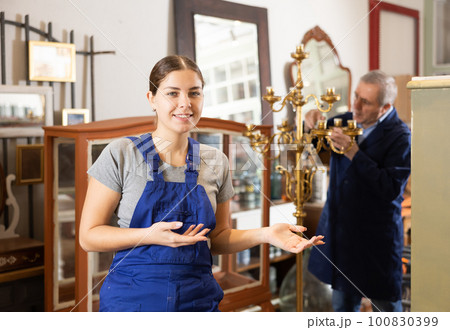 Happy young female furniture worker welcoming inside his workshop 100830399
