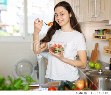 Woman eating vegetable salad at home kitchen Woman eating vegetable salad at home kitchen 100830646