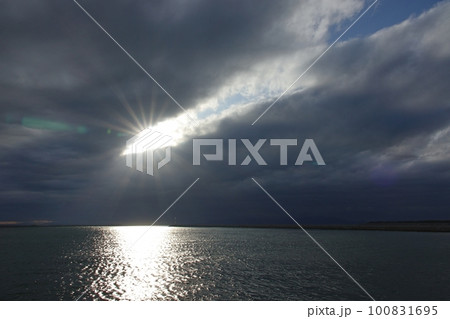 雲間から光が射した夕方の空と反射する港の海・春・広角・空主体・230318pm 100831695