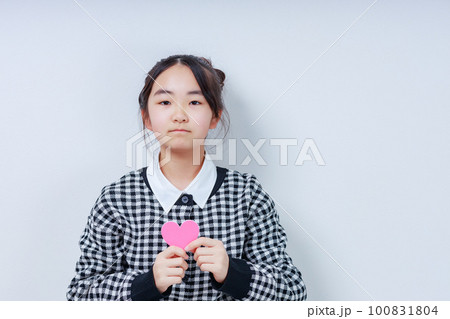 胸元でピンクのハートを持った女の子 胸元でピンクのハートを持った女の子 100831804