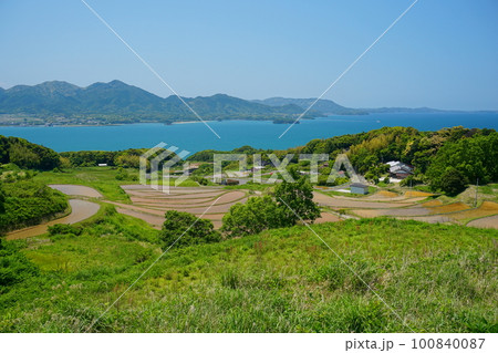 青空を背景にした山口県油谷湾の青い海と水張を終えた棚田の風景 青空を背景にした山口県油谷湾の青い海と水張を終えた棚田の風景 100840087