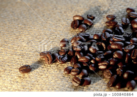 コーヒー用麻袋の上にロースト焙煎されたコーヒー豆が香りを放つ 100840864