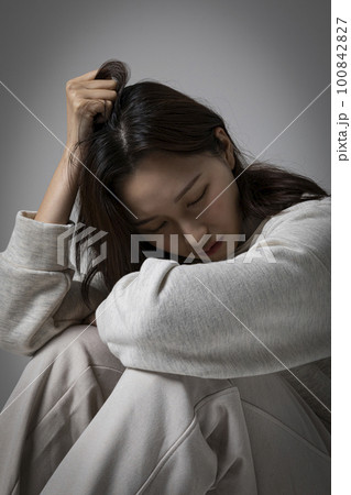 stressed, depressed Korean business woman in pink suit, frustrated 100842827