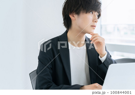 オフィスでパソコンに向かう若いビジネスマン 100844001