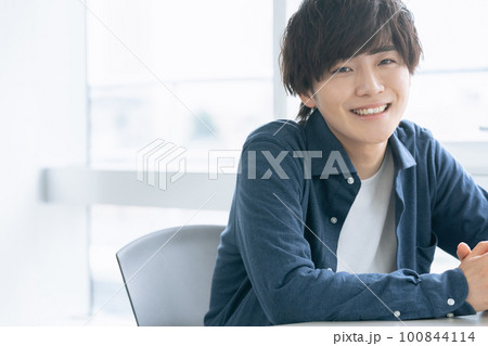 窓際で微笑む若い男性 100844114
