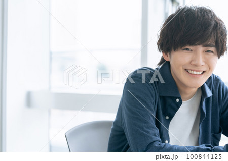 窓際で微笑む若い男性 窓際で微笑む若い男性 100844125