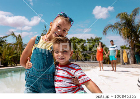 Portrait of happy biracial family taking smiling by the swimming pool 100845355