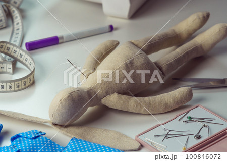 Stuffed rabbit toy with needles lying on table. Knitting hobby and business. Small hare toy next to sewing measure tape Stuffed rabbit toy with needles lying on table. Knitting hobby and business. Small hare toy next to sewing measure tape 100846072