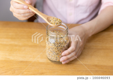 小鳥の餌を掬う女性 100846093