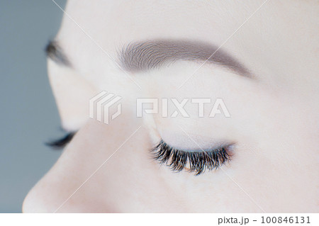 Close-up of closed eyes with long false eyelashes, perfect skin, flawless eyebrows of unrecognizable young woman. Macro. Close-up of closed eyes with long false eyelashes, perfect skin, flawless eyebrows of unrecognizable young woman. Macro. 100846131