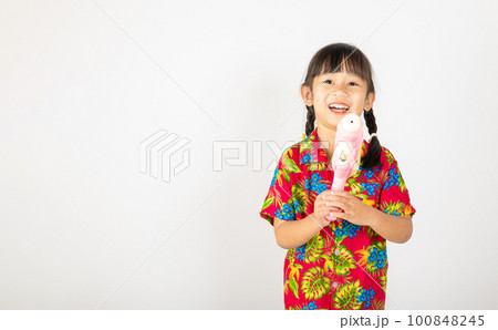 Happy Songkran Day, Asian kid girl with floral shirt hold water gun, Thai child funny hold toy water pistol and smile, isolated on white background, Thailand Songkran festival national culture concept 100848245