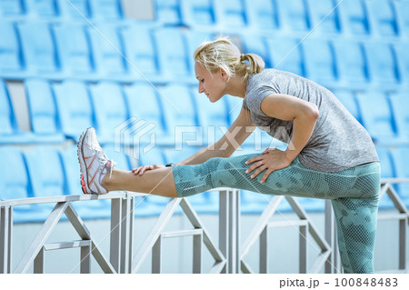female runner doing stretching exercise, tilt forward to leg, warm-up before athletics training female runner doing stretching exercise, tilt forward to leg, warm-up before athletics training 100848483