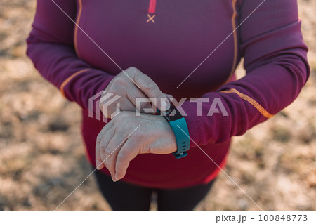 Close up image of sportsman checking his pulse on smart watch at city street. fitness, sport, people, technology and healthy lifestyle concept  100848773