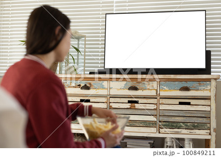 Caucasian young woman having french fries and watching tv while sitting at home, copy space 100849211