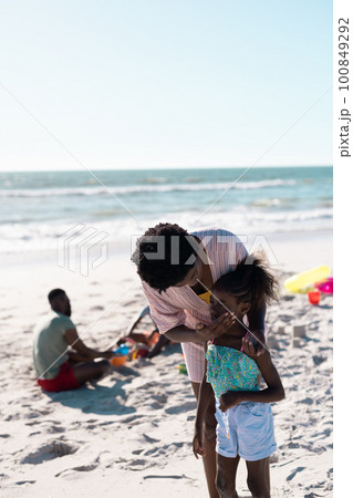 African american mother applying sunscreen on girl's face at beach against clear sky, copy space African american mother applying sunscreen on girl's face at beach against clear sky, copy space 100849292