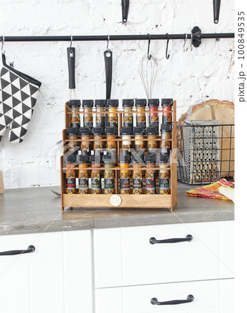 A set of glass jars with different spices in a wooden box in the kitchen. Kazan, 17 March 2023 100849535