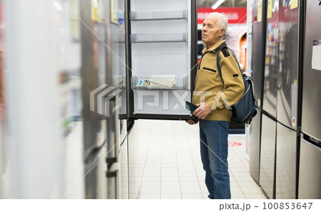 elderly man choosing refrigerator in showroom of electrical appliance store 100853647