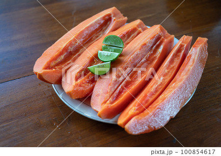 Sliced papaya with lime on table near swimming pool 100854617