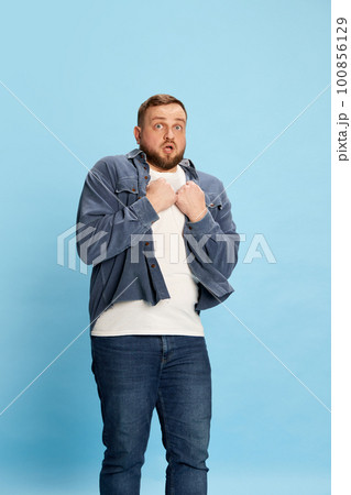 Handsome man standing and putting hands on chest with full of fear facial expression over blue background Handsome man standing and putting hands on chest with full of fear facial expression over blue background 100856129
