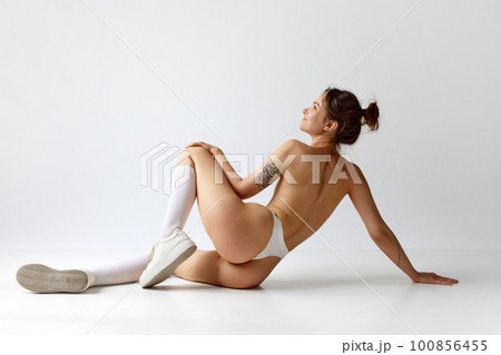 Rear view image of beautiful siling young girtl with fit body and naked textured back posing in underwear against grey studio background. Rear view image of beautiful siling young girtl with fit body and naked textured back posing in underwear against grey studio background. 100856455