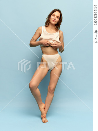 Full-length image of slim, beautiful, young girl in comfortable homewear posing against blue studio background. Full-length image of slim, beautiful, young girl in comfortable homewear posing against blue studio background. 100856514