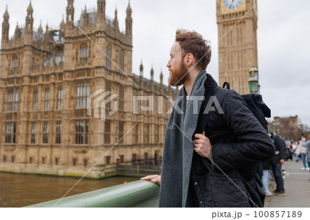 Male traveler with a backpack standing on a bridge near Big Ben in central London 100857189